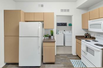 Kitchen with white appliances and adjacent laundry room
